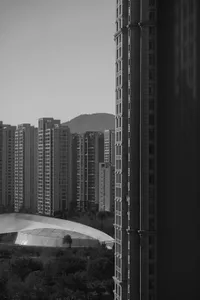 Black and white photograph of modern glass high-rise buildings in a cityscape with clouds.
