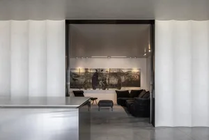 Modern minimalist interior featuring a concrete wall, a large abstract painting, and black furniture.