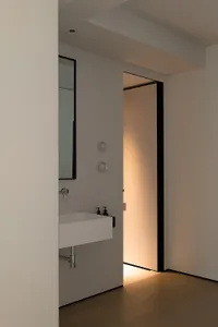 Modern minimalist bathroom featuring a concrete sink and mirror with a glass door.