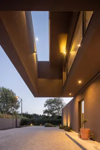 Concrete entrance and pathway leading up to a modern building with a skylight and warm lighting.