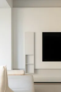 A modern minimalist living room featuring white concrete walls and furniture.