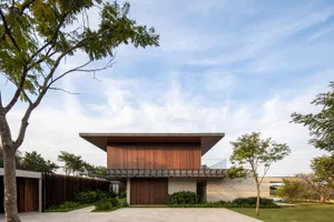 A minimalist modern residential architecture featuring a wooden exterior and glass windows.