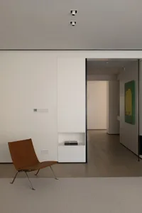 Modern minimalist living room with wood flooring and a brown leather chair.