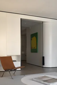 Modern minimalist residential space with white walls, a brown chair, and a green painting.