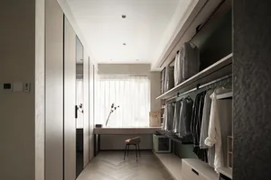 Modern closet with wooden floors, glass shelves, and white walls.