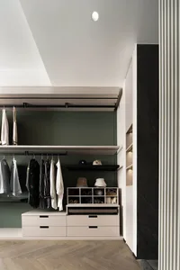 A modern closet with white, black, and green color scheme, featuring metal rods, wooden drawers, and shelves.