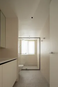 Modern bathroom with glass door, minimalistic design.