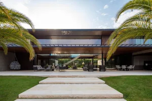 Modern residential house with glass walls, concrete steps, and wooden accents.