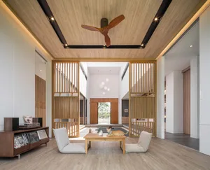 A minimalist living room featuring white walls, wooden paneling, and a low coffee table with a cat on it.