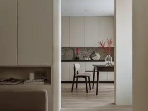 A modern minimalist residential kitchen featuring white marble countertops and wooden flooring.