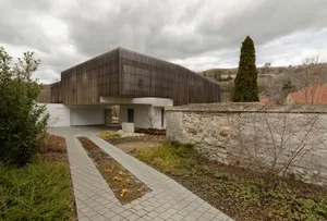 Modern residential building with wooden exterior panels and a stone pathway.