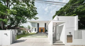 A modern residential exterior featuring white painted siding, large glass windows, and a concrete driveway.