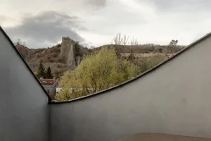 Minimalist interior with concrete walls and a view of a rocky hillside.