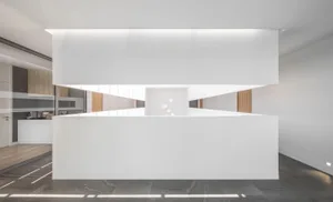 Modern office space with minimalist design, white walls, wooden accents, and black tiled flooring.