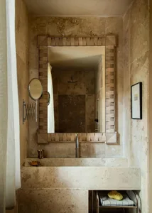A modern bathroom featuring a stone countertop with a rectangular mirror and metallic fixtures.