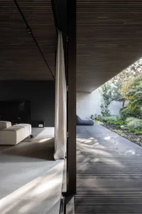 Modern interior design featuring a living space with concrete floors and walls, natural light, and outdoor elements.