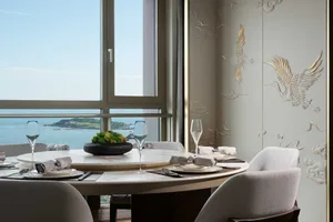 Modern dining room featuring glass, marble, and upholstered fabric seating with a view of the ocean.