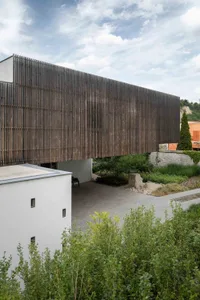 Modern architectural design featuring wooden fence and stone elements.