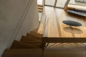 Modern interior design featuring wooden stairs with a concrete wall and a wooden table.