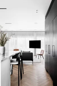 Modern living room featuring a marble floor, wooden cabinets, and a television mounted on the wall.