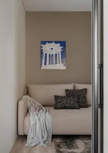 A modern lounge area featuring a grey fabric sofa adorned with grey pillows and a grey blanket draped over the arm.