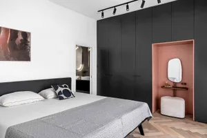 Modern minimalist bedroom featuring a black headboard bed, wooden floor, and black wardrobes.