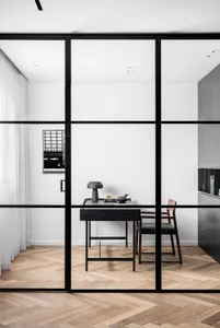 A sleek office space featuring a minimalist design with glass walls and wooden flooring.
