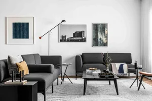 A modern living room featuring a white sofa and black coffee tables.