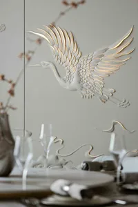 A detailed metal engraving of a flying crane on a gray wall.