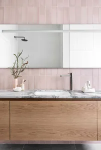 A minimalist bathroom with ceramic tiles features a vanity with a marble countertop, a wooden cabinet, a white sink, a mirror