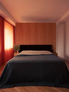 A minimalist bedroom with a wooden wall and a bed covered with blue textiles.