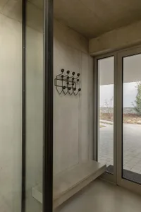 Modern minimalist entryway featuring concrete materials with a unique black coat hanger