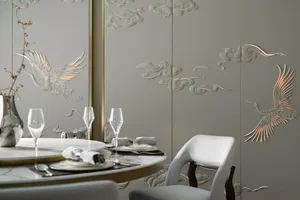 A modern dining room featuring metallic texture wall panels with bird and cloud motifs, table setting, and wine glasses.