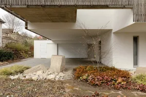 A modern house featuring a concrete driveway with a stone pathway and garden.