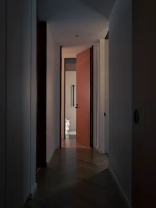 A modern interior corridor with wooden flooring and tiled walls.