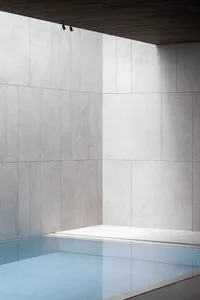A minimalist modern pool room with concrete walls and floor, featuring a clean and sleek design.
