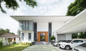 Modern residential house with a concrete exterior, featuring large windows and a carport.