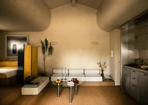 Minimalist studio apartment featuring a concrete floor, metal accents, and wooden furniture.