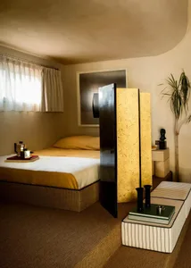 A minimalist bedroom featuring wooden panels, fabric bedding, and metal accents.