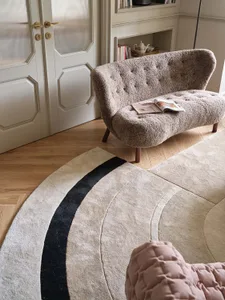Minimalist living room with white ceramic tiles, grey rug, and beige sofa.