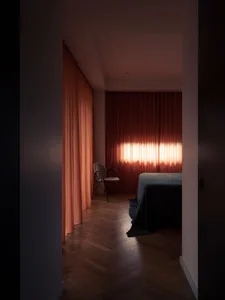 A bedroom with orange curtains and a wooden chair.