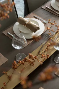 A well-set dining table with modern decor, including gold accents and a wooden centerpiece.