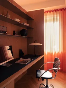 A modern minimalist home office with a wooden walls and desk, featuring a desk lamp and a chair.