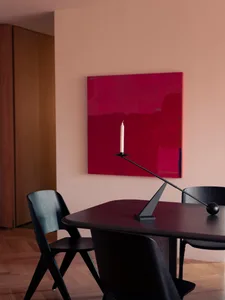 A minimalist interior design featuring a modern metal table with a single candle holder and a red abstract painting on the wa