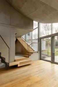 Modern interior space featuring a wooden staircase with concrete walls and floor.