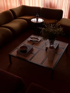 Modern industrial living room with brown couch, coffee table, and floral arrangement.