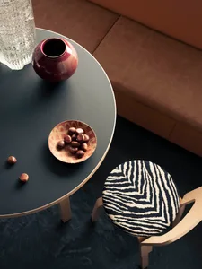 A modern interior scene featuring a table with a wooden base and a ceramic vase, adorned with a bowl of chestnuts and a glass