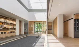 A modern living room with tall ceilings, large windows, and a minimalist design featuring wooden and concrete elements.