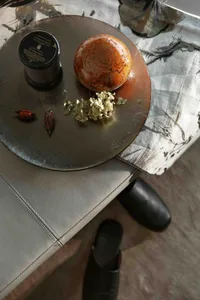 Aromatic candle and decorative marble object on a round metallic tray with dried flowers and decorative elements.