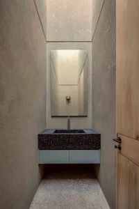 Modern minimalist bathroom featuring a black and white speckled sink counter, a rectangular mirror, and wooden door.